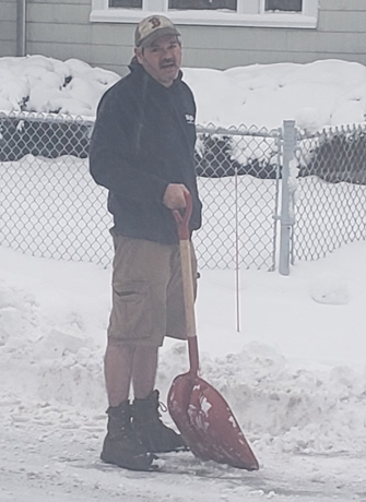 Man shoveling snow in shorts in Watertown