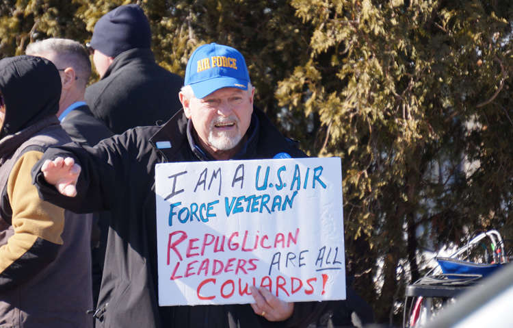 Man holds sign that says he's a USAF veteran and that all Republicans are cowards