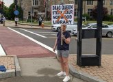 Woman holding sign against drag-queen story hour at the Norwood library