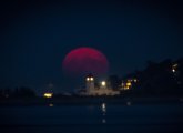 Blood-red hunter's moon rising over the water