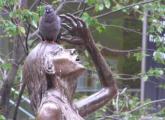 Irish Famine Memorial statue with a pigeon on her head