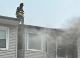 Firefighter on top of building with fire on Dorchester Avenue