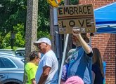 Man with sign reading Embrace Love