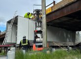 Workers try to figure out how to get trailer out from under overpass