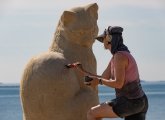 Artist working on giant cat made of sand