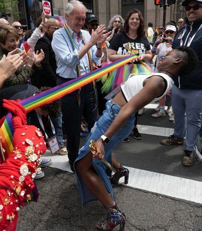 Adrianna Boulin, president of Boston Pride of the People, limbos below the opening ribbon of Pride parade