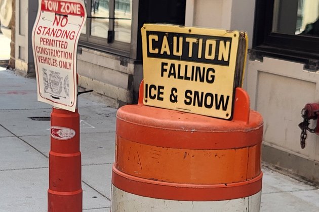 Traffic barrel topped by sign reading: CAUTION Falling Ice and snow