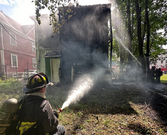 Firefighter aims water at smoldering Thetford Avenue home