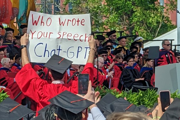 Student holds sign in protest against David Zaslow, far right