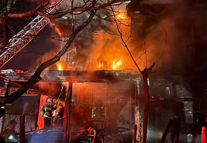 House on fire on Draper Street, with firefighters on what's left of the front porch