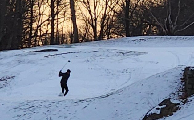 Fore! Golfer tees off in the snow at George Wright today