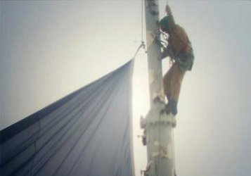 Guy attaching Patriots flag to the top of the Old Hancock in Boston