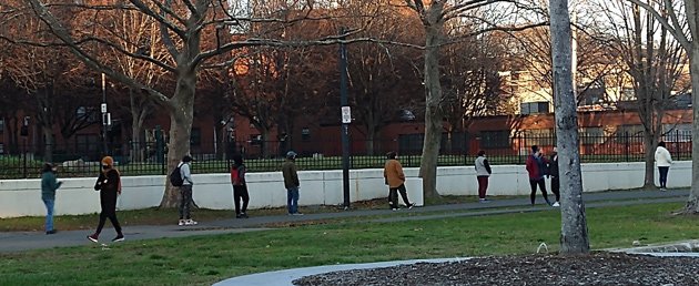 Socially distanced Orange Line riders wait for a bus at Jackson