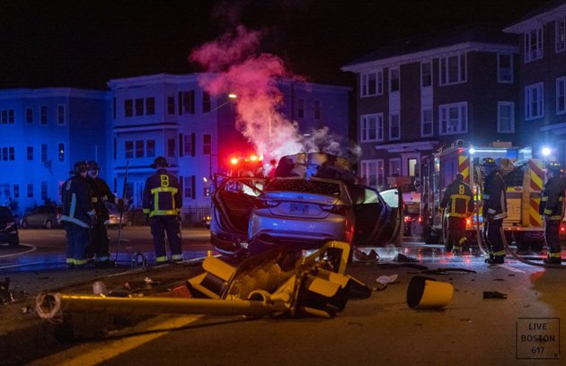 Crash scene in Mattapan - traffic light destroyed, car bursts into flames