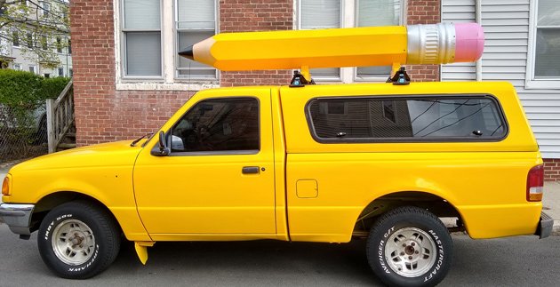 Yellow pickup truck with giant pencil on top