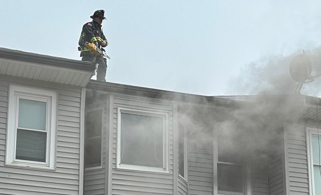 Firefighter on top of building with fire on Dorchester Avenue