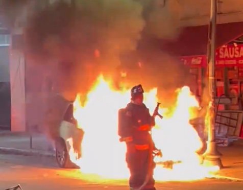 Firefighter in front of flaming car