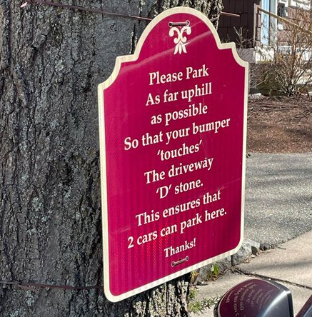 Sign that urges people to pull up as far as possible so two people can park between driveways