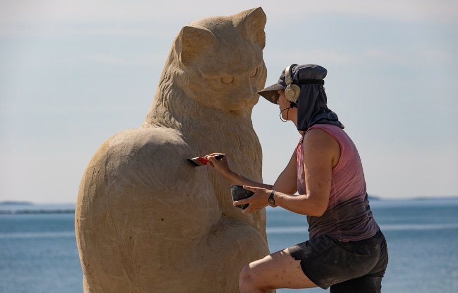 Artist working on giant cat made of sand