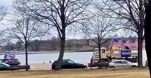 A couple of vehicles adorned with American and Trump flags