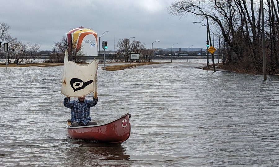 Man in canoe with handheld sail to catch the winds off Dorchester Bay