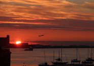 Sunrise over Boston Harbor with a plane taking off