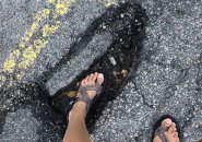 Woman up to her ankle in Jamaica Plain pothole