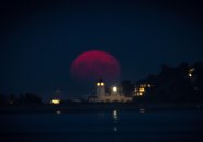 Blood-red hunter's moon rising over the water