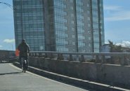 Person riding a Blue Bike onto the turnpike