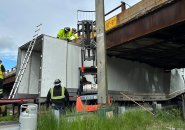 Workers try to figure out how to get trailer out from under overpass