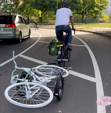 Bicyclist pulling white ghost bike